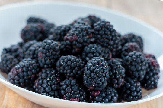 Fresh ripe blackberries in white bowl, shallow depth of field