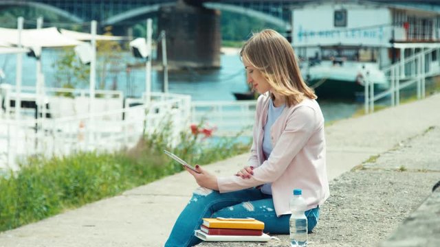 Young adult using tablet pc outdoors near river