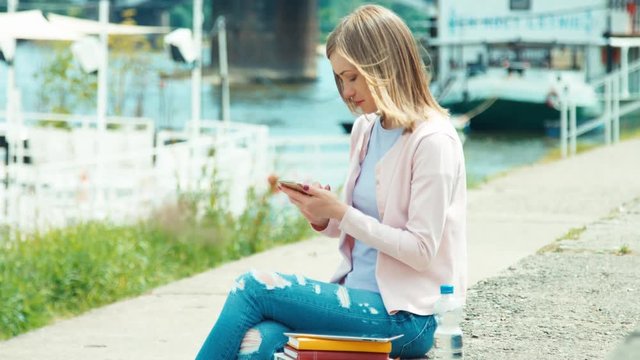 Young adult using mobile phone outdoors near river