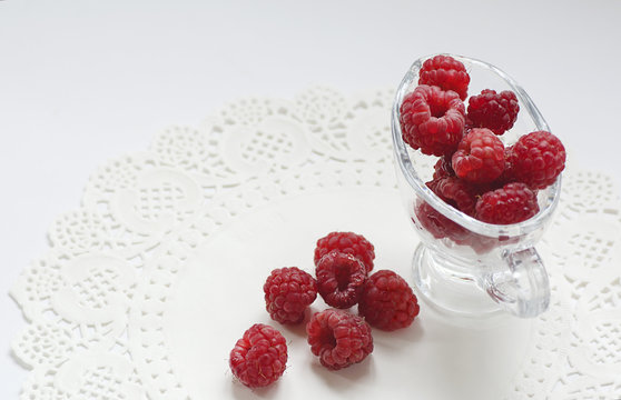 ripe raspberry on the table in a transparent glass vase on white background