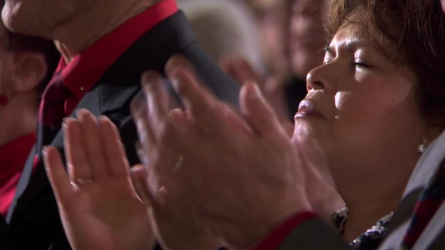 Close view of woman's face in profile as she prays and claps
