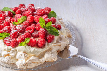 Meringue Pavlova  with whipped cream and fresh raspberries.