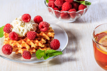 Waffles garnished with mascarpone and raspberries.