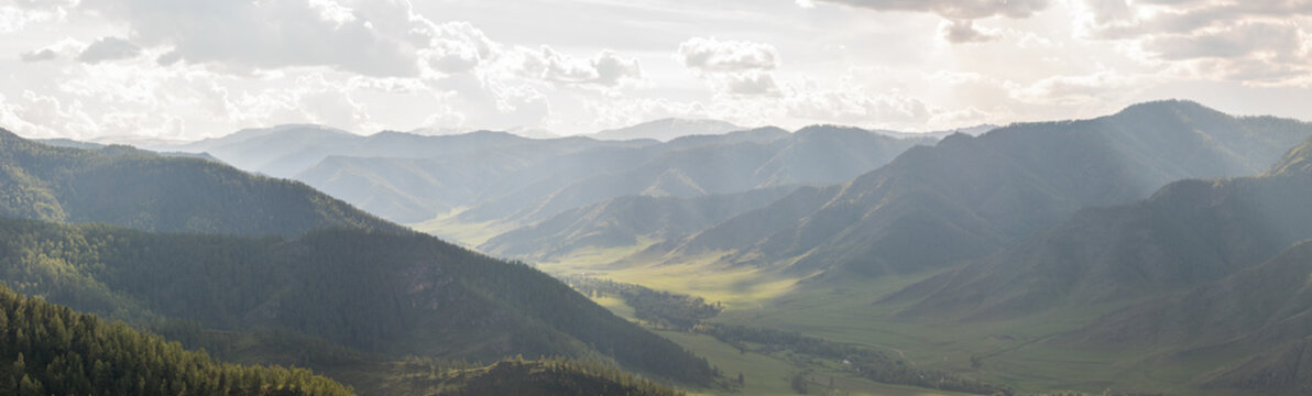 Fototapeta Mountain valley in the rays of the midday sun and fog