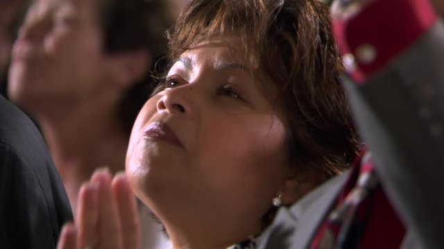 Close-up of woman's face as she sings among other members of a congregation