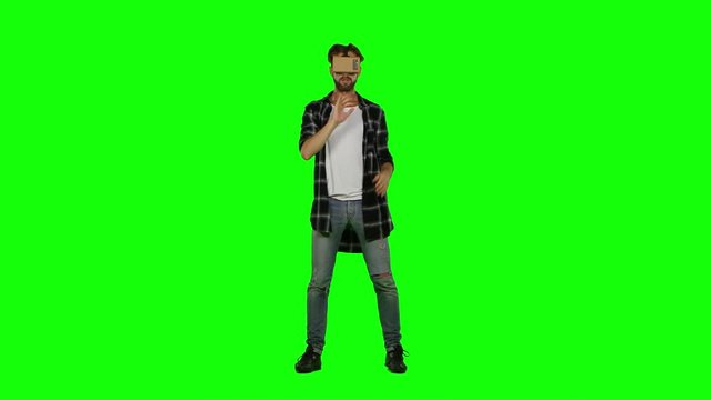 Young man with VR virtual reality headset on his head. Green screen