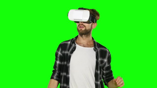 Man in a virtual reality mask looks around. Green screen. Close up