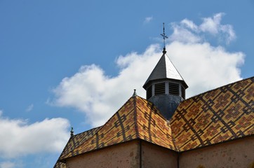 Fototapeta na wymiar Toits de tuiles vernissées et clocher du prieuré d'Ambierle