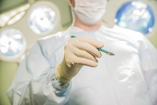 closeup of a doctor holding a scalpel on the background of the operating room