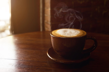 cup of hot coffee on table in cafe with morning light - vintage and dark color tone styles