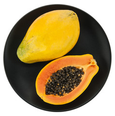 Papaya on white plate, black background.