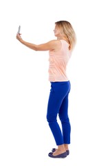 back view of standing young beautiful  woman  and using a mobile