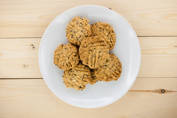 Place the cookies on a white plate on a wooden floor.
