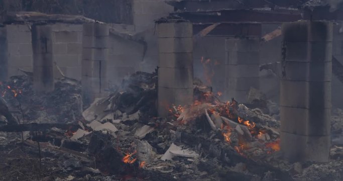 Pile Of Flaming Rubble Surrounding A Concrete Foundation Support Of A House Destroyed By Fire