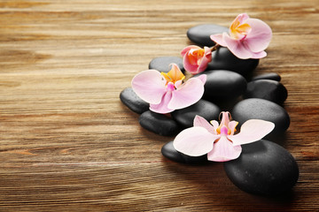 Fototapeta na wymiar Spa stones and orchid flowers on wooden background