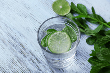 Infused lime water with mint on wooden background