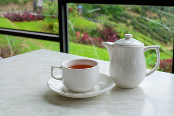 White cup of tea and teapot on white marble table