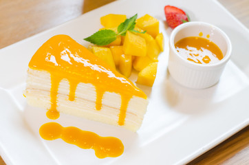 crepe cake with mango sauce. Orange crepe cake. set on white pla