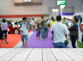 Wood table top on blur of people in motor show with background