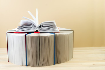 Open book, stack of hardback books on wooden table. Back to school. Copy space