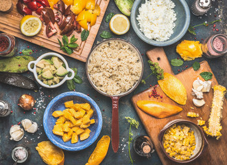 Quinoa salad preparation with vegetables and fruits cooking ingredients on dark rustic background, top view. Superfood, healthy Eating or vegan food concept