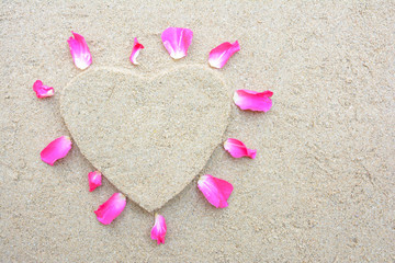 Heart shape and pink rose petal with sand background