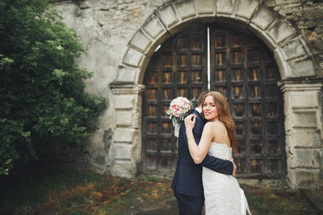 Happy wedding couple hugging and smiling each other on background old castle