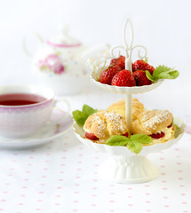 Cream puffs or profiterole filled with whipped cream served with strawberries in plateau on a breakfast table
