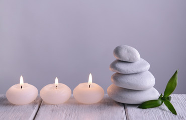 Fototapeta na wymiar White spa stones with candles on gray background