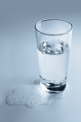 Glass and some mineral water on light background