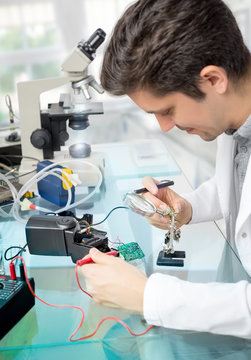 Young male tech repairs flash electronic unit