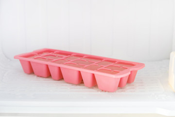Colorful plastic ice tray in the freezer compartment of the refrigerator.