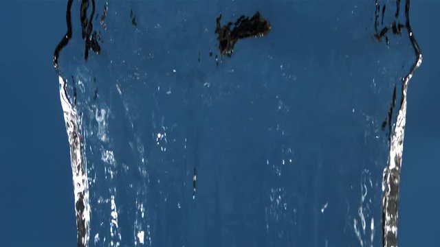 Ultra-slow motion sheet of water narrowing to a stream in center of blue frame