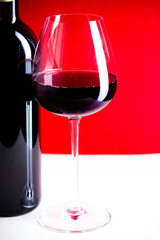 glass of red wine is on the red background