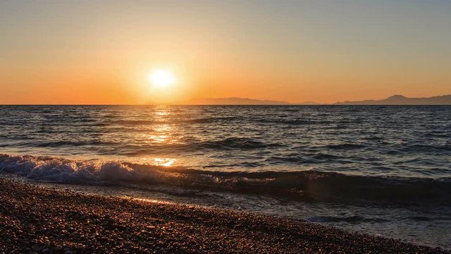 sun sets behind horizon and the rocks in sea Greece Aegean evening