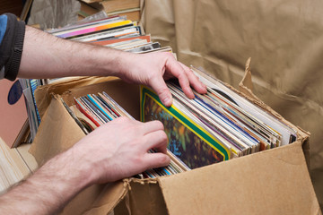 Retro styled image of a collection of old vinyl record lp's with sleeves on a wooden background. Browsing through vinyl records collection. Music background. Copy space