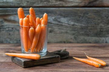 Baby carrots in a glass on rustic wooden background