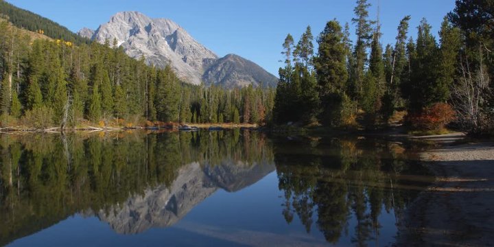 Mirror image reflection of Grand Tetons and evergreens at edge of String Lake