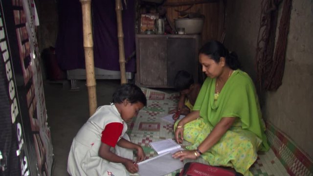 Mother and children doing schoolwork in Calcutta home