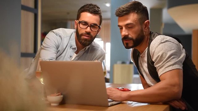 Trendy guys in bar connected with laptop