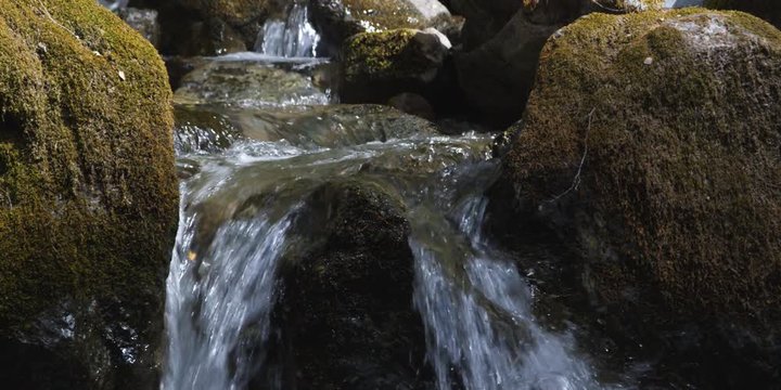 Stream cascading over terraced ledges framed by mossy boulders