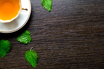 herbal nettle tea in a porcelain Cup on a dark wooden background