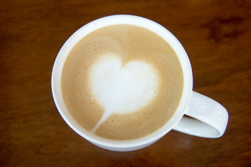 white heart latte art in white cup on wooden table