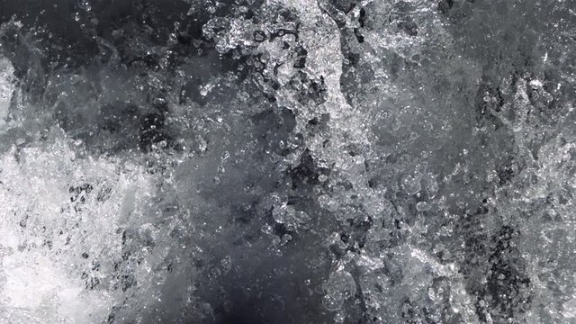 Close-up ultra-slow motion water splashing at the foot of a falls