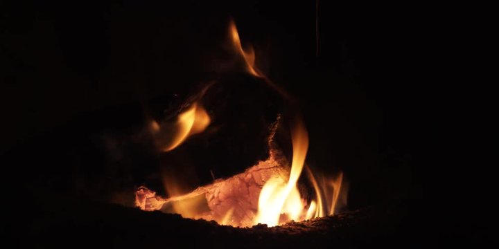 Flames flickering over a burning log on a small fire