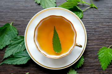 herbal nettle tea in a porcelain Cup on a dark wooden background