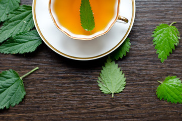 herbal nettle tea in a porcelain Cup on a dark wooden background