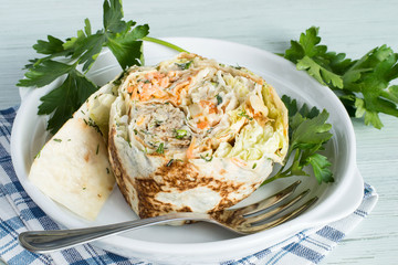 Roll filled with fish and vegetable.    Roll filled with fish and vegetable on a white plate on a...