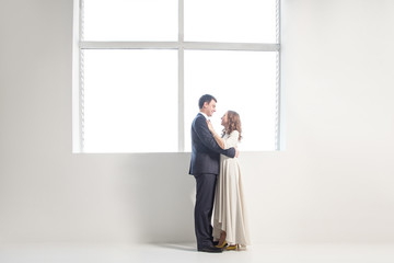 Happy wedding couple posing in bright room embracing each other