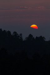 Silhouette of globe orange sun set over mountain top with nice cloudy sky.